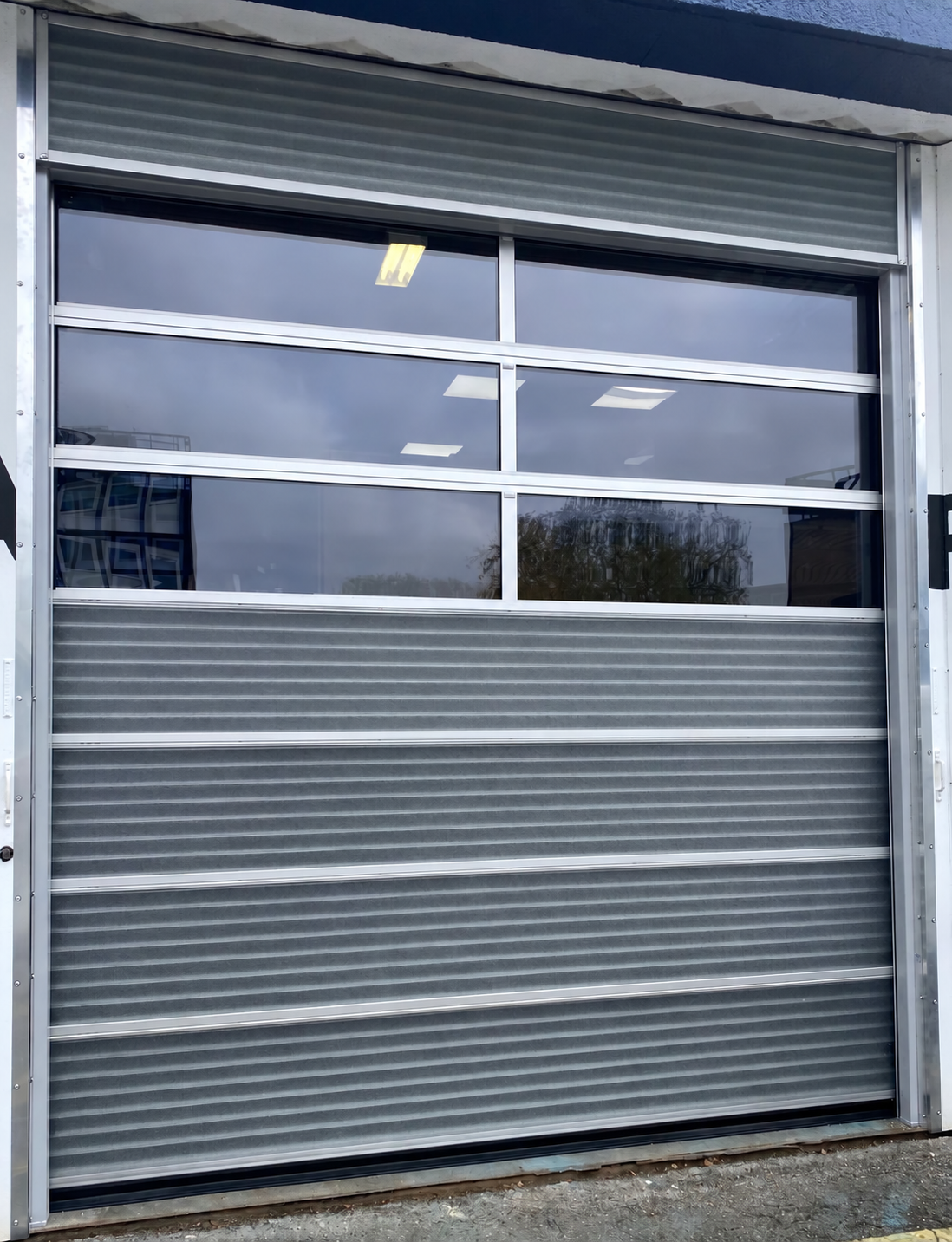 Grey sectional overhead door with glazed panels and metal tracks